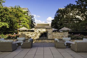 Central outdoor lounge with stone fireplace & multi-level terrace featuring a formal garden